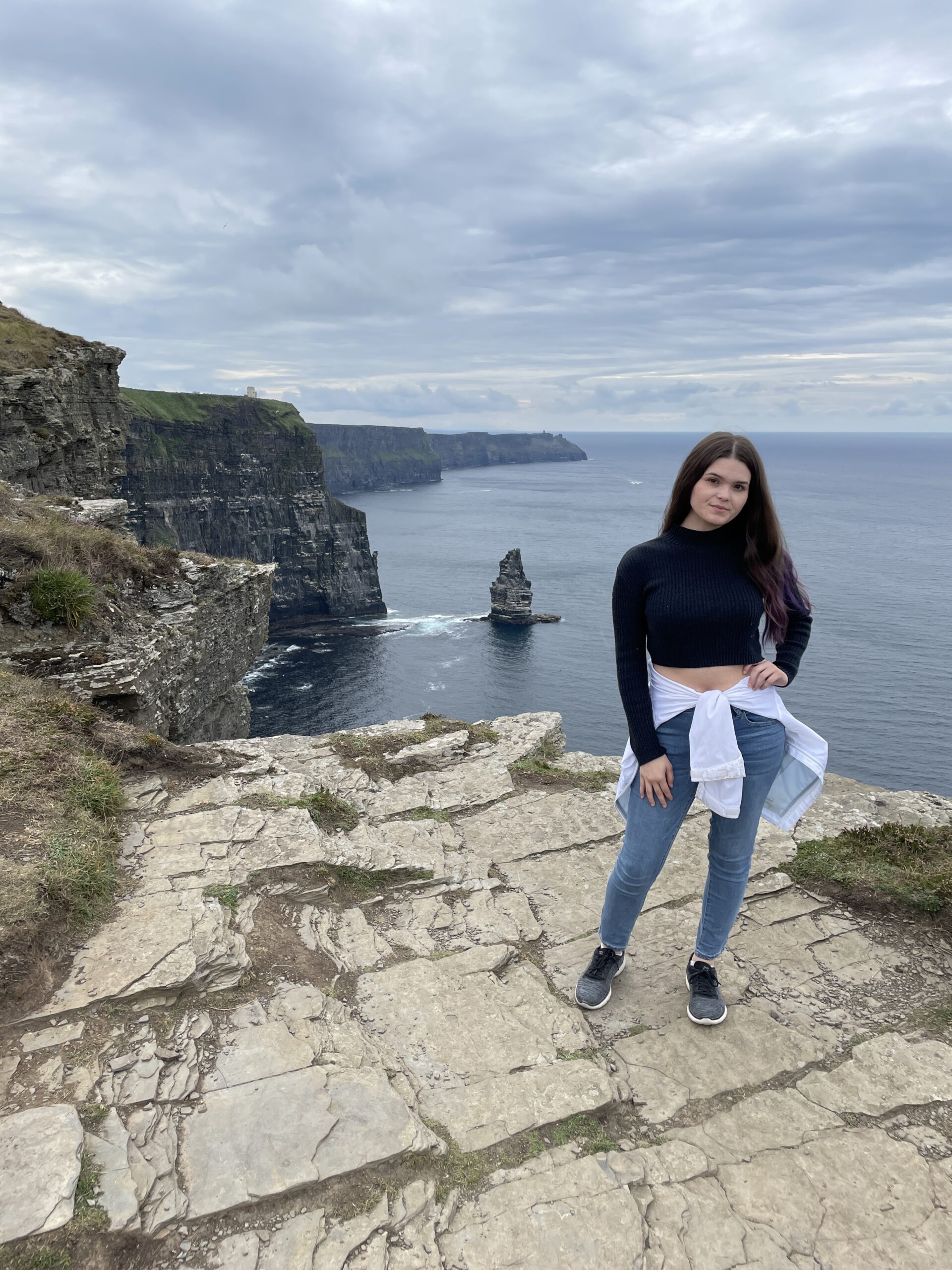 Solo travel girl in Ireland by the sea on the Cliffs of Moher.